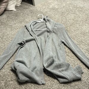 Light grey open sweater with pockets and a hood.